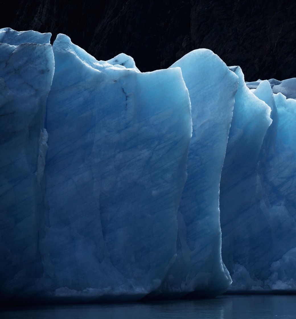 A wall of blue glacial ice at dusk